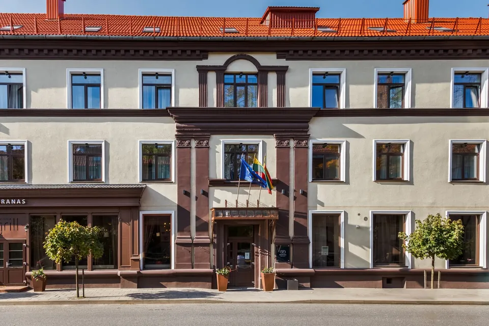 Art Hotel Bohema Klaipėdoje: pastato fasadas su portiku ir vėliavomis